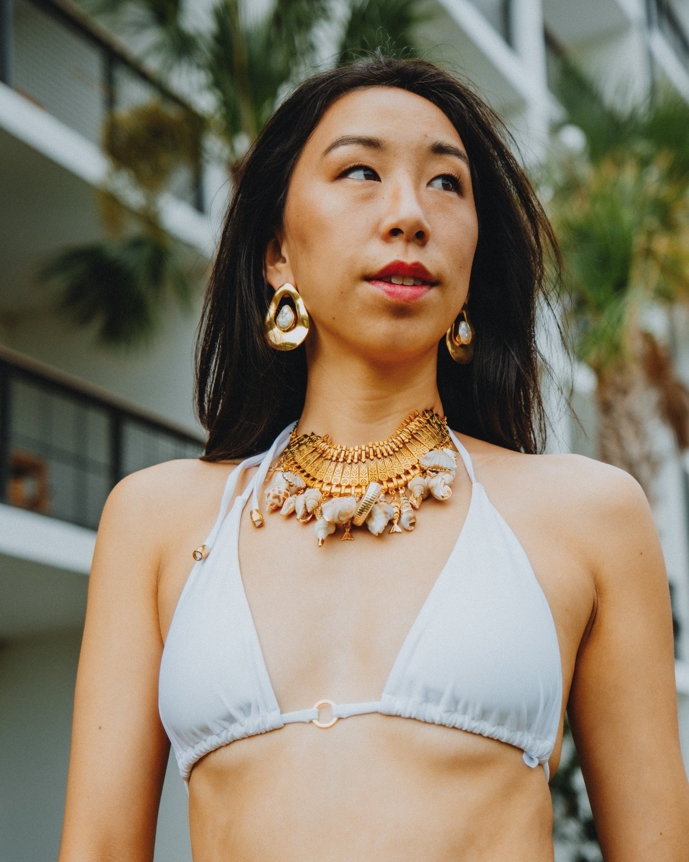 Woman wearing a light gray bikini with gold jewelry outdoors