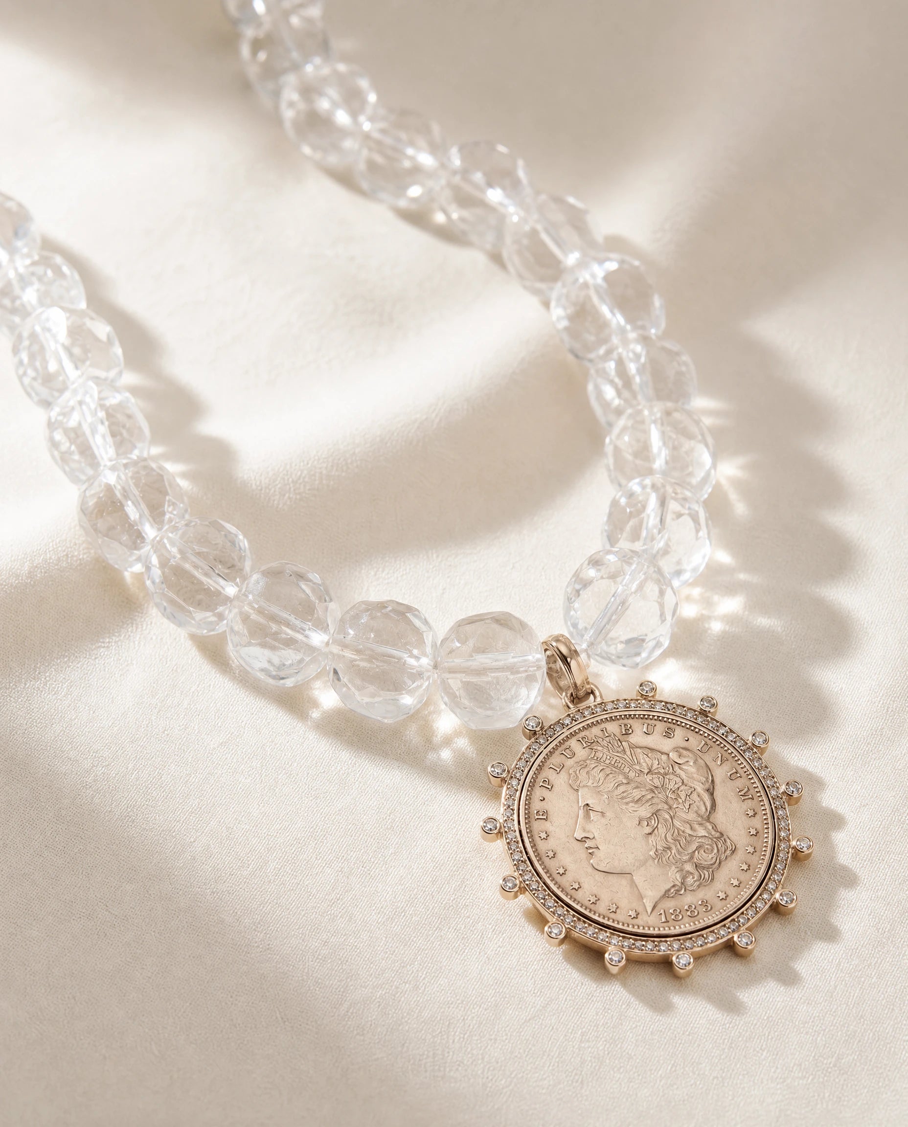 Necklace with clear beads and a coin pendant on a light background